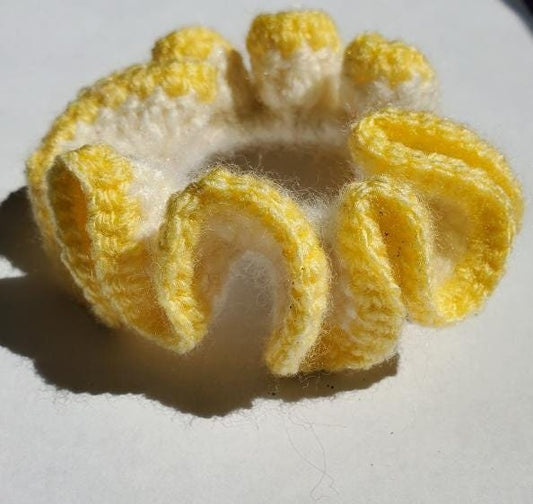 Chouchou en crochet blanc avec bordure jaune. Contient un élastique en son centre.